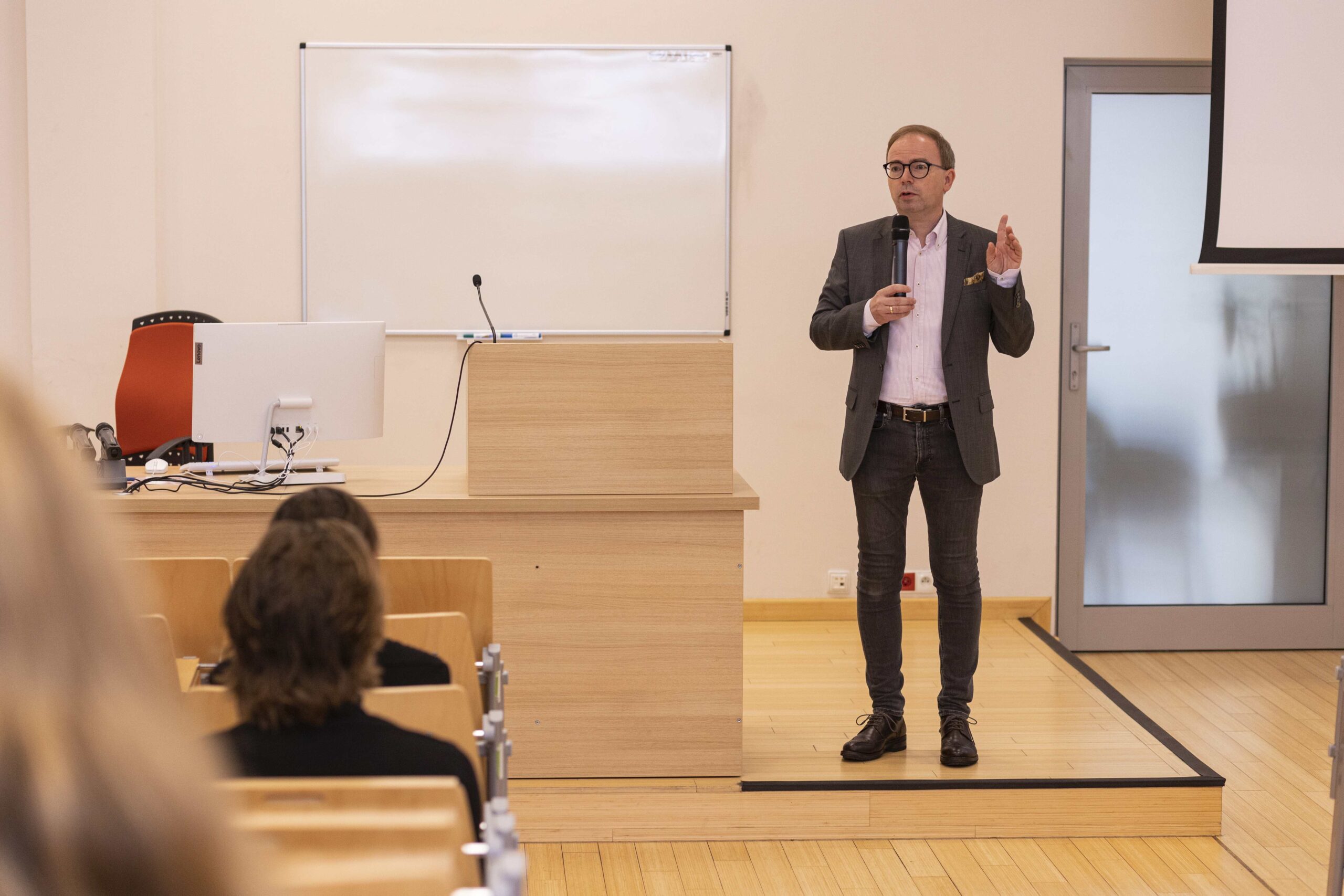 A man in a suit gives a presentation in front of a group of listeners, illustrating his ideas and concepts.
