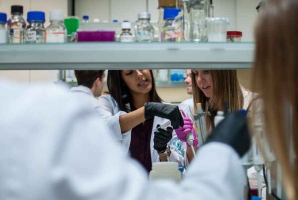 A diverse group of individuals in lab coats collaborating on a scientific project in a laboratory setting.