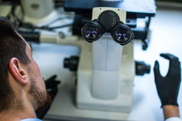 A man studies a microscope in a lab, concentrating on his work and the details of the specimens before him.