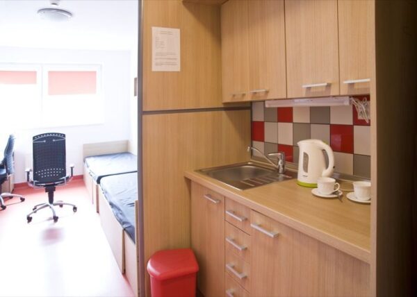 A quaint kitchen space with a sink and a desk, illustrating a harmonious blend of utility and simplicity in a limited area.